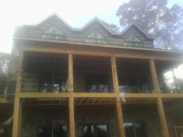 Dormers and porch framing on a large log home under construction — Roof Coating work by our crew in Hunters