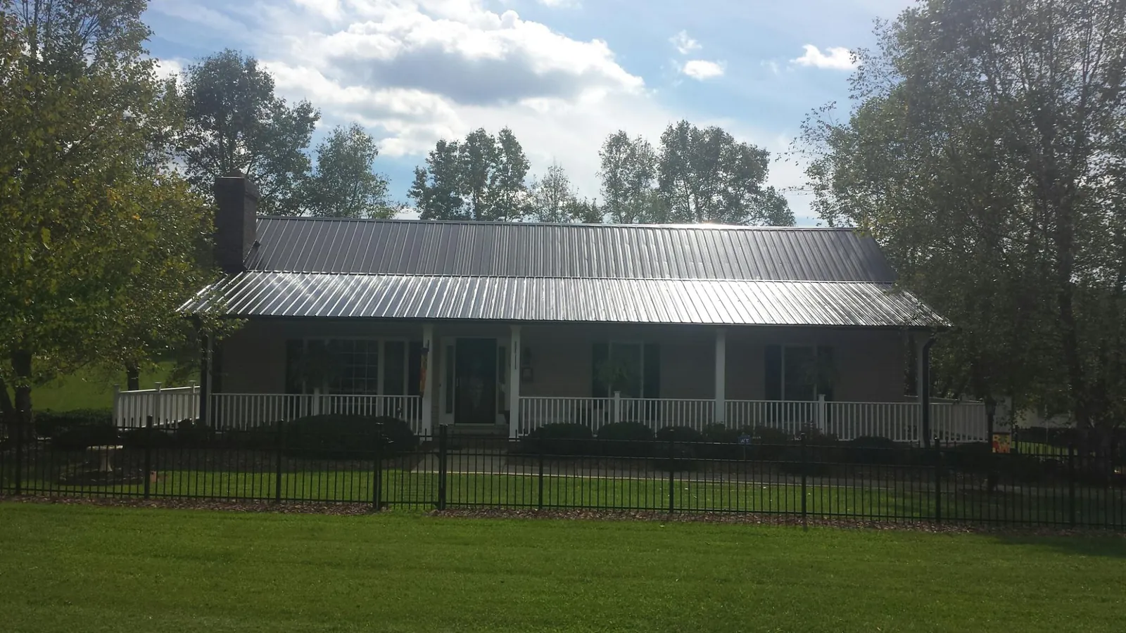 Gray metal roof on a brick ranch with a full width front porch — Gutter Guard Installation work by our crew in Hunters