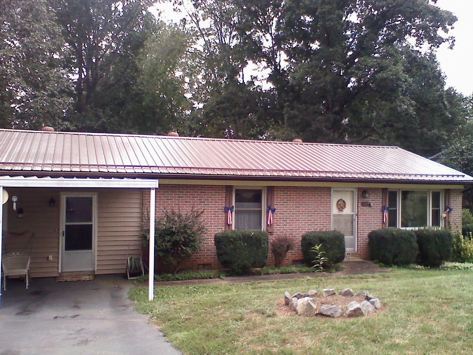 Bronze metal roof and carport on a brick ranch home — Roof Repair work by our crew in Hunters