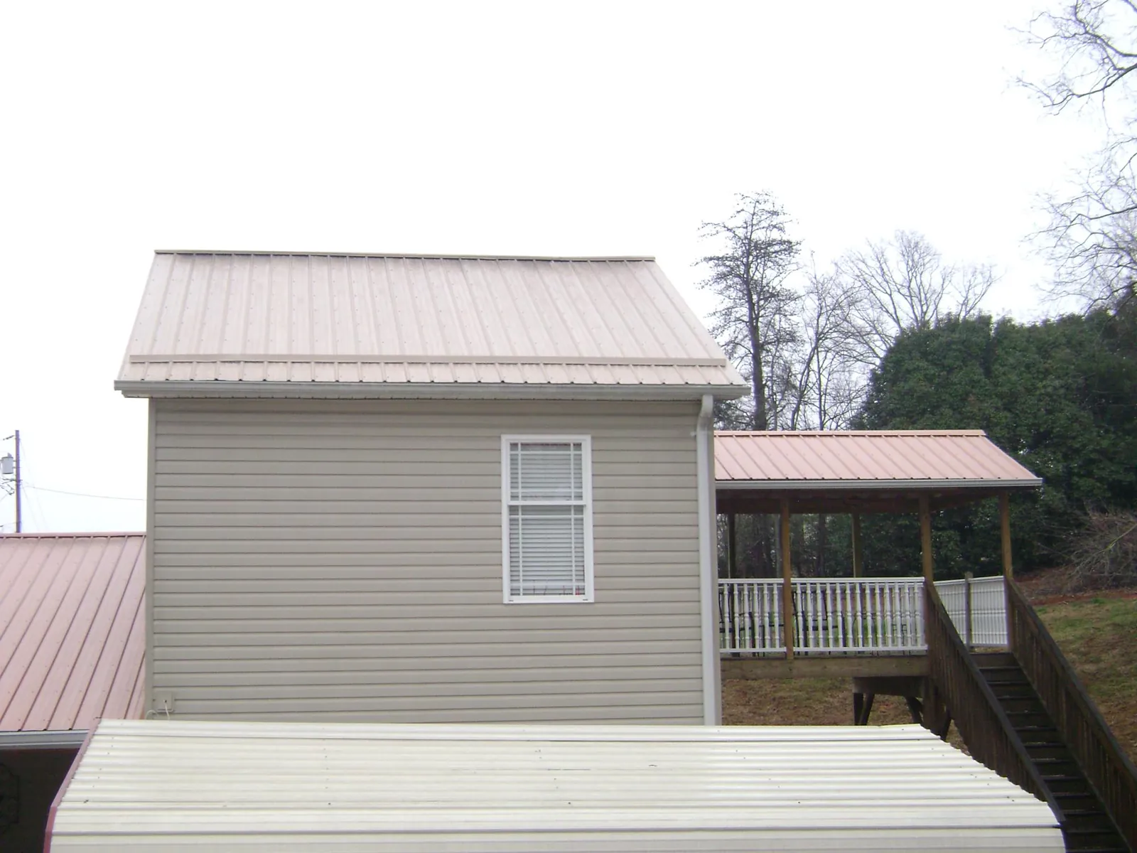 Tan metal roofs on a two story addition and attached porch, from a Roof Replacement job in Hunters